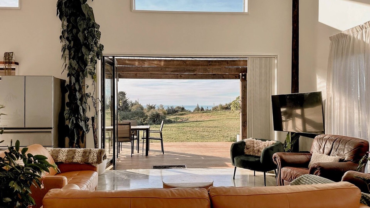Hokitika House | The open-plan kitchen, dining and lounge area is the heart of the home, perfect for sharing a meal, curling up with a good book, or simply watching the weather roll in through the floor-to-ceiling windows.