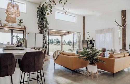 Hokitika House | The open-plan kitchen, dining and lounge area is the heart of the home, perfect for sharing a meal, curling up with a good book, or simply watching the weather roll in through the floor-to-ceiling windows.