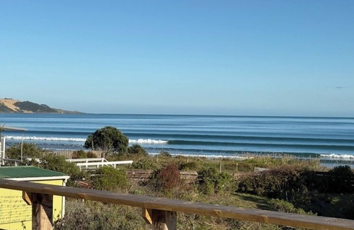 Ahipara House | Watch the waves from the large, sunny deck of this 1950's bach. Pet friendly.