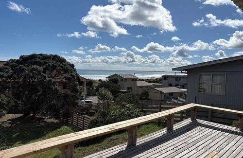 Ahipara House | Watch the waves from the large, sunny deck of this 1950's bach. Pet friendly.